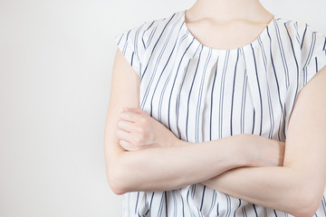 腕組みするオフィスカジュアルな服装の女性