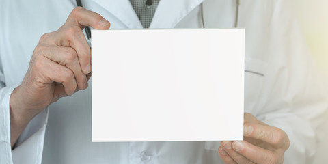 big white empty sheet with place for mockup in hands of old doctor