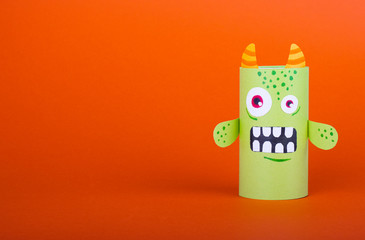 green scary monster made from a roll of toilet paper on orange background