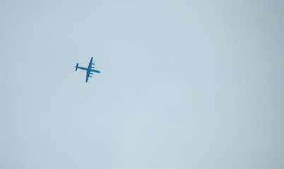 Motorized military aircraft in the sky above the ground.