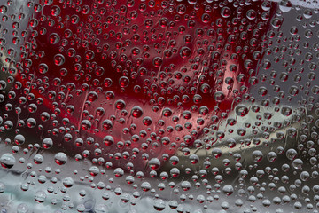 Red drops of water flow down on the multi-colored mirror ice surface. Abstract fantasy. 