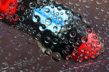 Transparent raindrops flow down on the multi-colored background. Abstract fantasy.