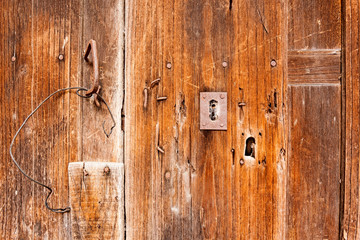 Fototapeta na wymiar An old wooden door with a lot of nailed iron spikes and a rusty lock with a cobweb.