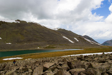 Alpine mountain lake landscape at the daytime, colorful landscape, snow and clouds