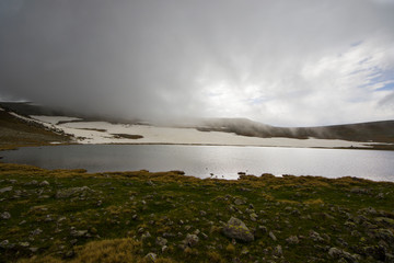 Alpine mountain lake landscape at the daytime, colorful landscape, snow and clouds
