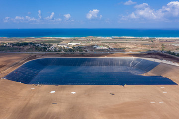 Water reservoir construction site with newly installed plastic lining sheets, Aerial view.