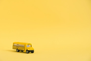 Back to school concept. Traditional yellow school bus on yellow background. Transfer to school. Yellow toy model school bus.