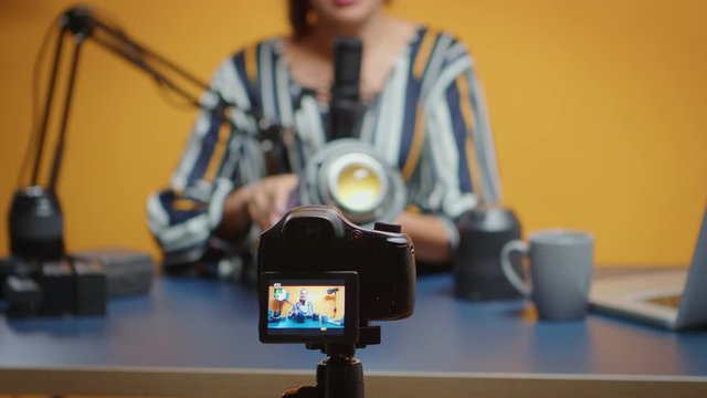 Close up of influencer recording on camera video light review. Social media star making online interent content about professional video equipment for web subscribers and distribution