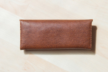 Leather and leopard textured glasses case on a light-colored parquet floor.