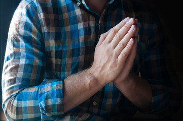 The man's hands are folded in prayer. Christian believer's prayer