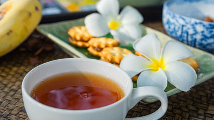 Tea time in warm afternoon, round white tea cup and fowers and snakes on table.