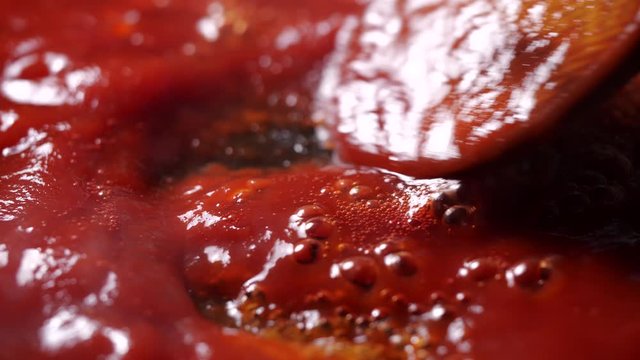 Close-up of boiling red tomato sauce in a pan with steam for making pizza or pasta