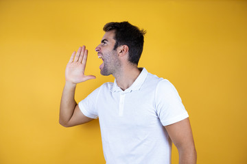 Young fitness man over yellow isolated background shouting and screaming loud to side with hand on mouth. Communication concept.