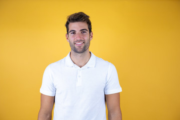 Young handsome man wearing casual white t-shirt standing over yellow background with a happy and...