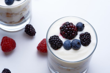 Glass of granola, yogurt, raspberries and blueberries on a white background
