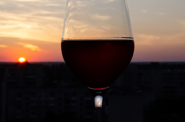 Close-up glass with red wine on a blurred background with copy space. Part of a wine glass on a sunset sky background. Sunset. Beautiful sunset with a glass of wine in the foreground.