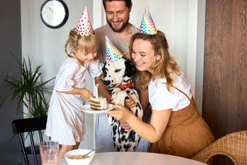 beautiful happy family celebrate birthday together, sit in the kitchen wearing party hats, man...