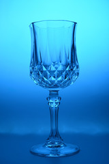 Wineglass on the light background. Fine cristal glassware concept. Vertical, toned in blue