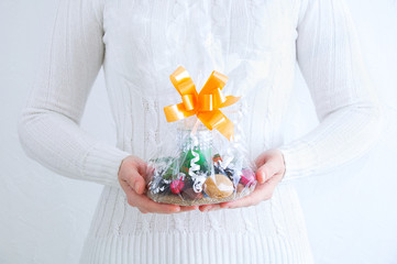 Caucasian woman in a white sweater with Christmas present in her hands. White background.