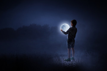 Fototapeta na wymiar Boy holding moon at night