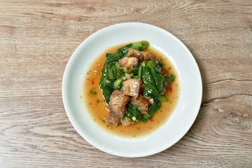 spicy fried Chinese kale with slice crispy pork in soybean and oyster sauce on plate