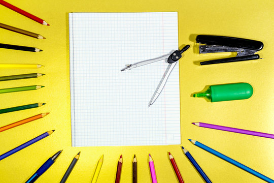 Stationery And Colored Pencils With A Notebook Are Spread Out On A Yellow Surface