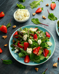 Goats cheese and strawberry summer salad served with nigella and sesame seeds drizzled with runny honey