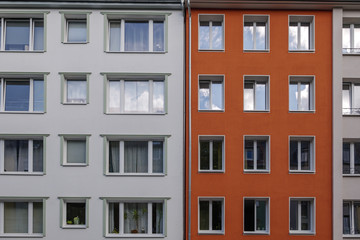 Fototapeta na wymiar Outdoor sunny exterior front view, typical facade of modern residence or apartment in city of Europe with various rectangular windows, white and red wall.
