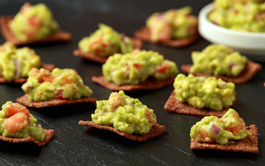 Avocado Guacamole with chipotle and poblano whole grain tortilla chips on rustic stone board