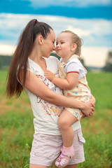 Smiling mother holds her daughter in her arms.