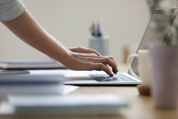 Close up young businesswoman typing message on laptop keyboard, communicating with client online,...