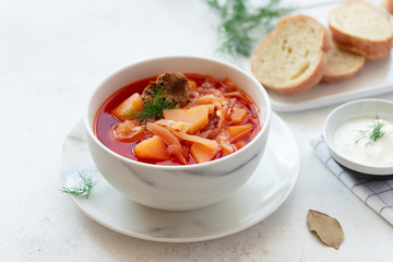 Traditional Russian Ukrainian red borscht in a white bowl, served with sour cream, dill and bread. Tasty homemade vegetable soup. close-up. White background. copy space
