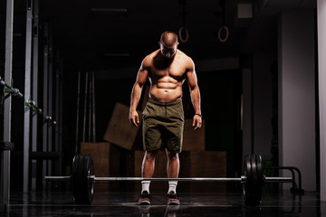 Fototapeta na wymiar Muscular athlete preparing to lift barbell. Crossfit trainer in a fitness studio.