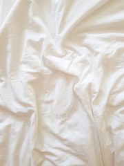 An unfilled bed after sleeping with white linen. Good morning. The concept of rest and relaxation.