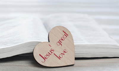 Open holy Bible on the table. Heart love. Inscription Great love of Jesus
