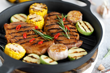 Grilled meat with vegetables in a cast iron grill pan. Grilled pork with grilled vegetables
