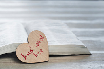Open holy Bible on the table. Heart love. Inscription Great love of Jesus