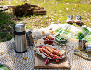 outdoor autumn lifestyle: picnic in the meadow with grilled sausages with fresh vegetables on the...