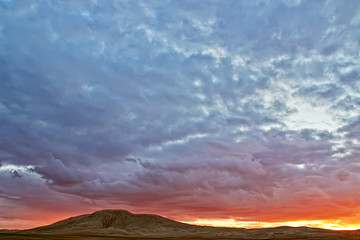 Naklejka na ściany i meble Evening cloudy sky over the sand dunes.