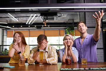 young caucasian football fans making facepalm, disappointed with game loss, bar