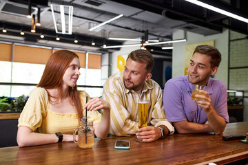 portrait of young caucasian people meeting for the first time in a bar, beautiful women and handsome guys talk and have fun, drink beverages