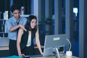 Businesspeople in the office at night working late, Two young businesspeople working overtime...