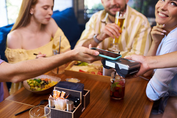 clients pay for meal via smartphone, in restaurant. contactless payment concept