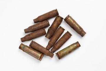 Ten rusty cartridges from a machine gun scattered on a white background