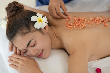 Obraz na płótnie Canvas Woman enjoying in spa salon, Beauty therapist pouring salt scrub on woman back at health spa
