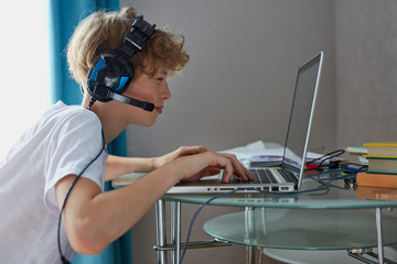 lazy teenager boy play computer games, sit in headphones, looking at screen of laptop, free time at...