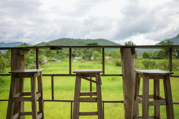 Fototapeta na wymiar wooden table and chair for drink coffee and watching view of mountain farm landscape in sunlight