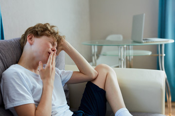 sleepy teenager boy sit alone at home, have some rest, in the morning