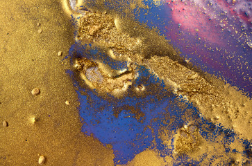 Piles of gold sequins on blue liquid ink background. Abstract pattern.