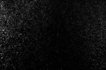 Abstract splashes of water on black background. Freeze motion of white particles. Rain, snow overlay texture.